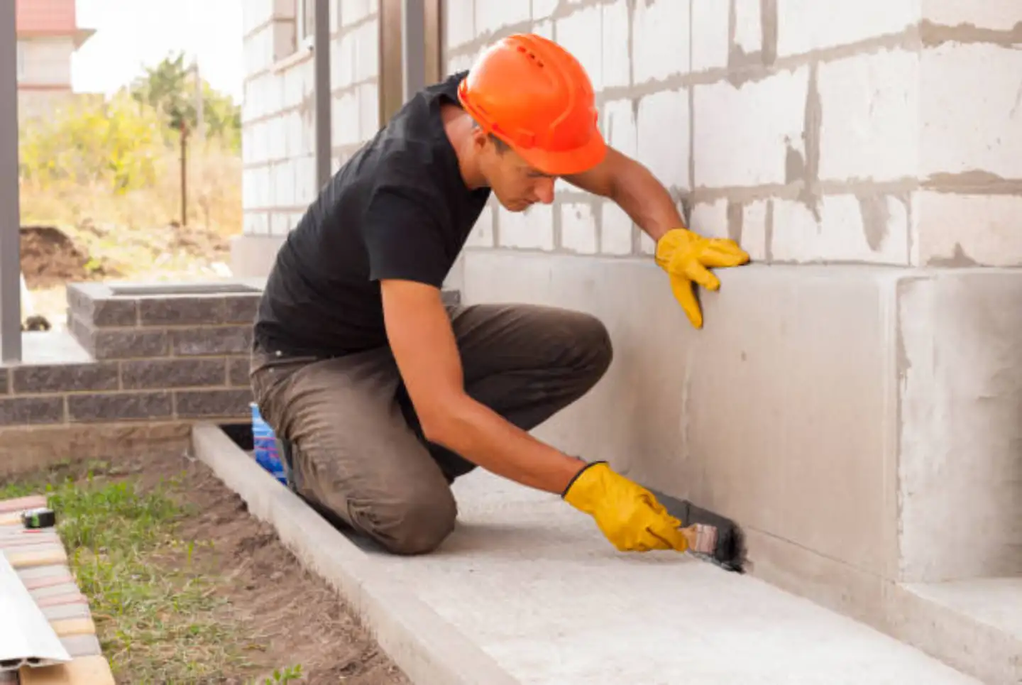 Foundation specialist applying sealant to concrete block foundation